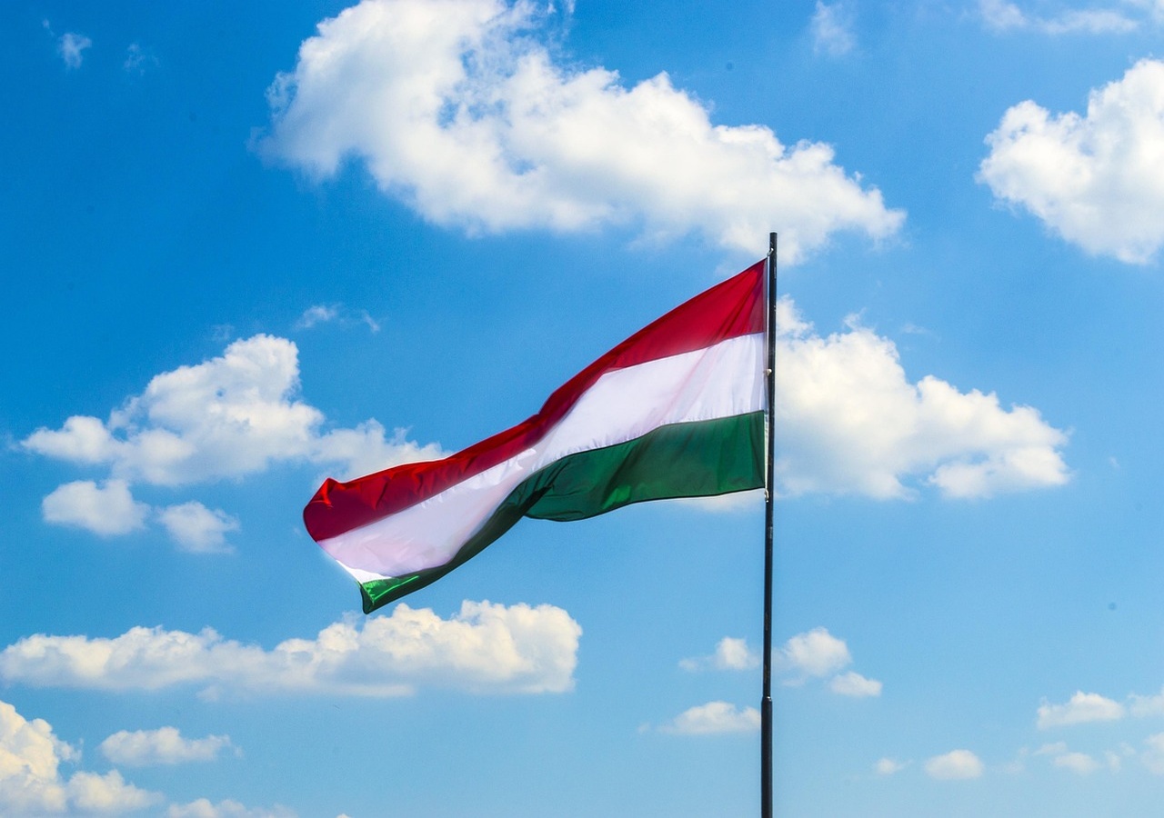 Magyar zászló kék égen, ahogy a piros, fehér és zöld sávok lobognak a szélben