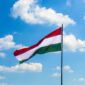 Magyar zászló kék égen, ahogy a piros, fehér és zöld sávok lobognak a szélben